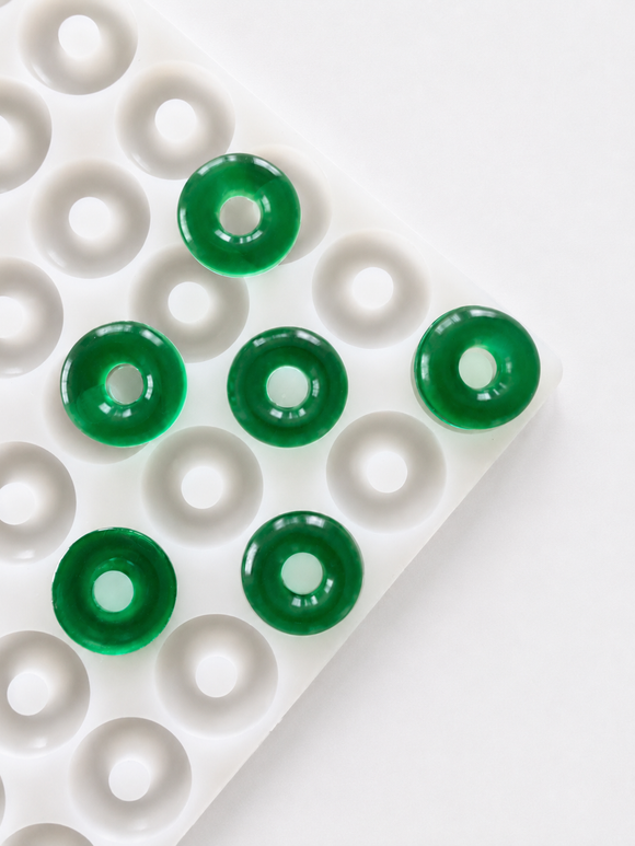 Molde para gomitas de aro de melocotón de 3.4 mL - 108 cavidades - vista en ángulo, con muestras de gomitas verde esmeralda, translucidas