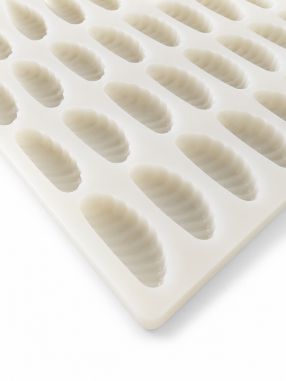 A close-up of a white silicone mold tray with multiple elongated, ribbed oval cavities, shown on a clean white background.