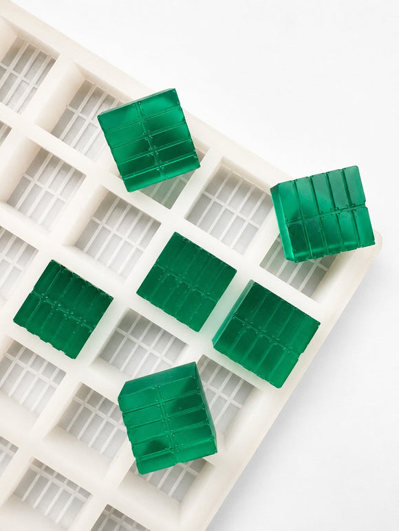 Angled view of a 7.4mL brick gummy mold with 70 cavities and emerald green brick gummies on a white background